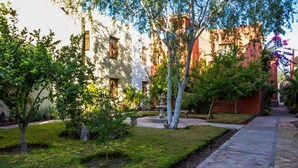 A courtyard with a stone pathway, trees, and a fountain. - Casa Colette FN 307 2 BR by Casago (Loreto)