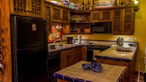 A kitchen with wooden cabinets, a black refrigerator, a microwave, and a tiled island. - Casa Colette FN 307 2 BR by Casago (Loreto)