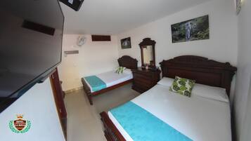 A hotel room with two single beds, a wooden headboard, a dresser, a mirror, and a television.