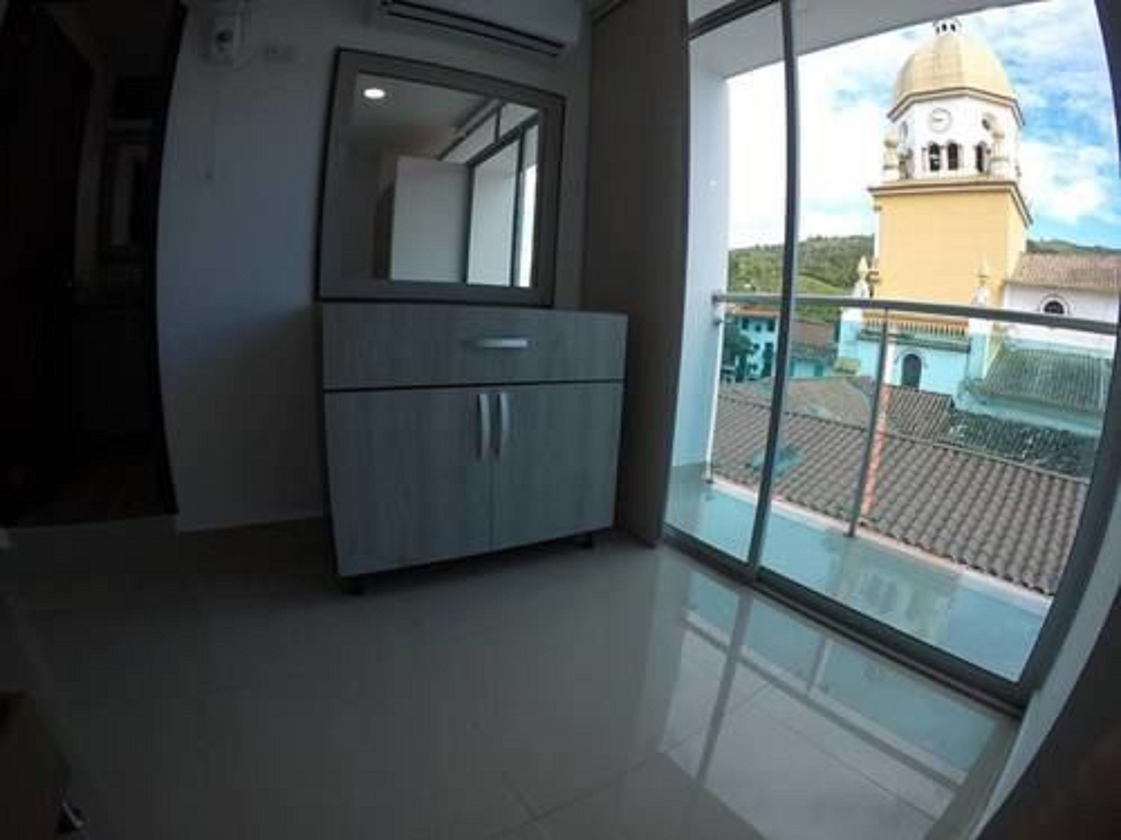 Una habitación con un ventanal grande, un armario de madera y vista a un edificio con cúpula.