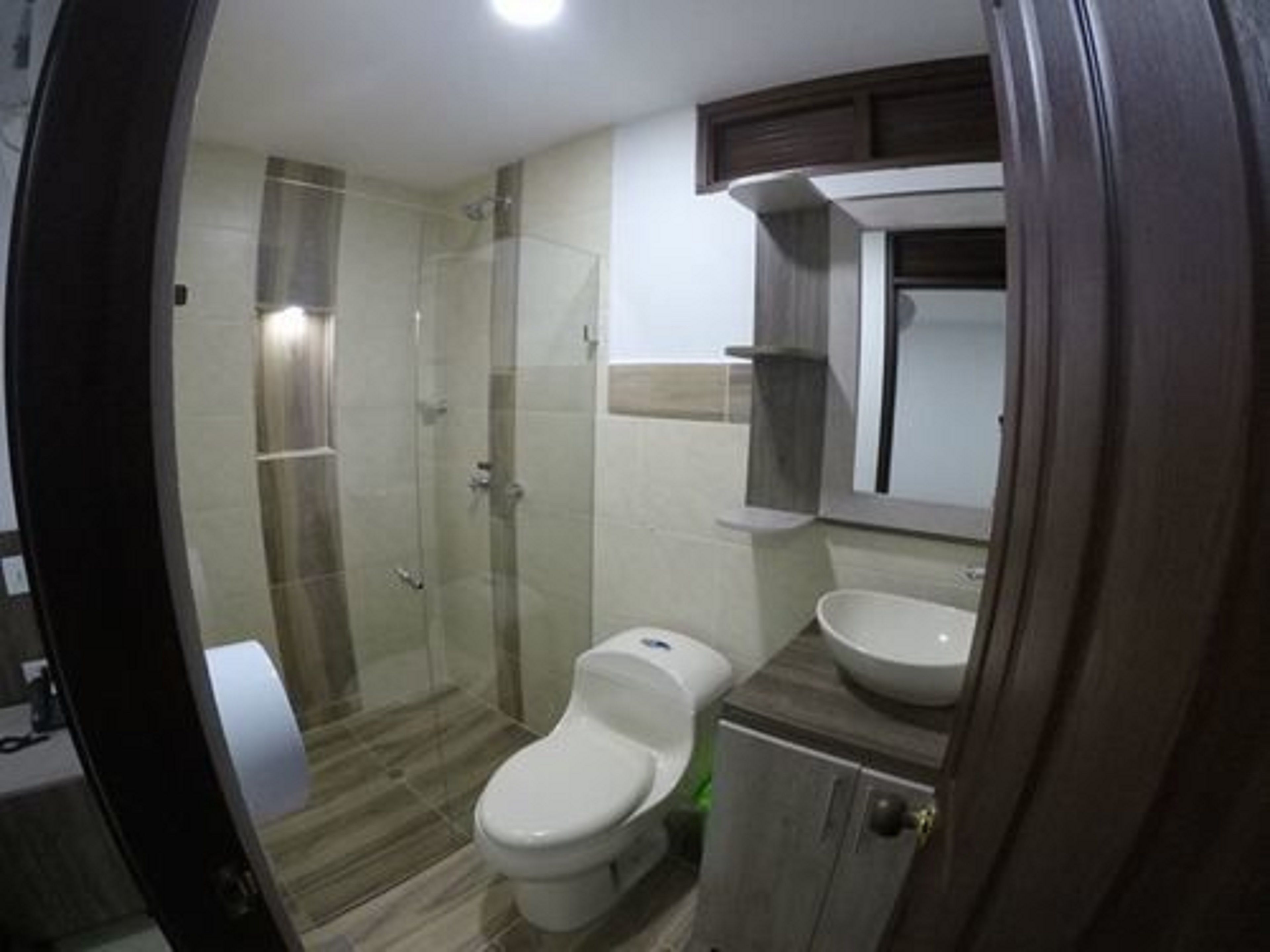 A bathroom with a glass shower enclosure, a toilet, a sink, and a cabinet.