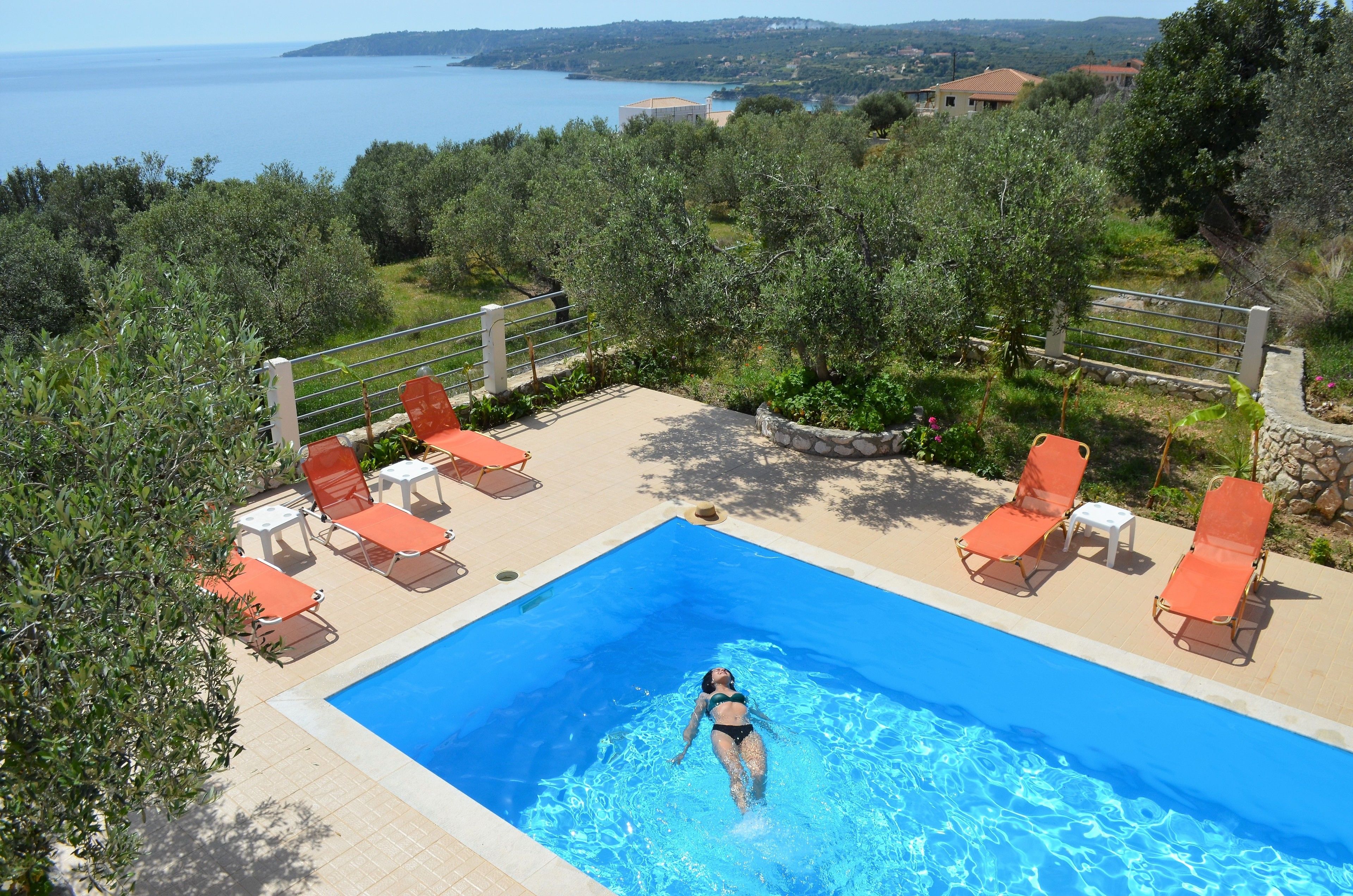A swimming pool with lounge chairs and a view of the sea.