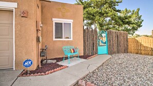 A house with a brown stucco exterior, a blue mailbox, a bench, and a wooden fence. - Mountain-View Albuquerque Townhome w/ Patio! (Albuquerque)