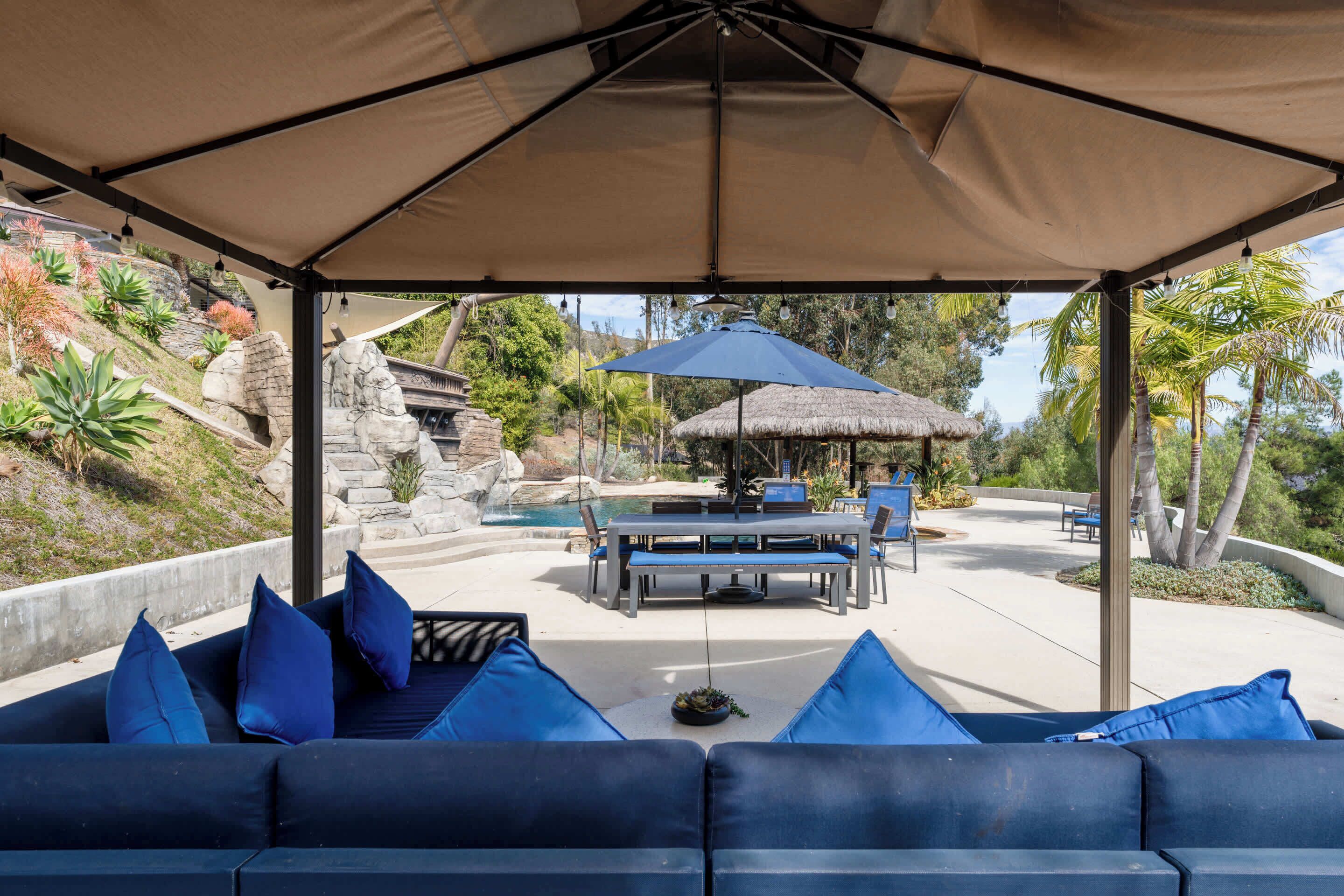 An outdoor seating area with blue cushions, a table, and an umbrella.