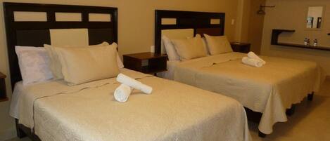 Two twin beds with headboards, a small table, and a nightstand with a lamp.