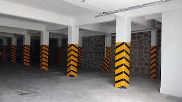 A parking garage with white pillars and black and yellow chevron markings.