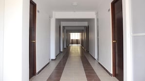 A long, straight hallway with doors on both sides, leading to a staircase at the end.