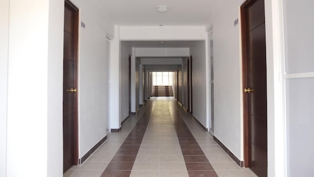 A long, straight hallway with doors on both sides, leading to a staircase at the end. - Hotel Gold (El Oro de Hidalgo)