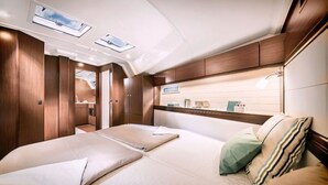 A compact, well-lit interior with a bed, bedside tables, and a small kitchenette.