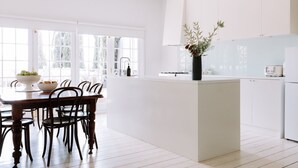A modern kitchen with white cabinetry, a central island, and a dining area with wooden chairs.