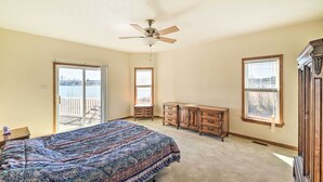 Een slaapkamer met een bed, een dressoir, een plafondventilator en uitzicht op een balkon.