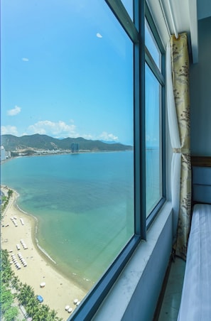 Una habitación con un ventanal grande que da a una playa y un paisaje urbano.