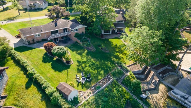 An aerial view of a residential area with two houses, a well-maintained lawn, and a small dock by a body of water. - Private Beach • Hot Tub • Sauna • Game Room •  No-Wake Cove + Party Cove Access (Coloma)