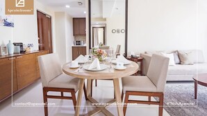 A modern living/dining area with a round table set for dining, a sofa, and a mirror.