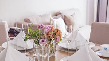 A dining table set with white napkins, clear glasses, and a centerpiece of flowers.