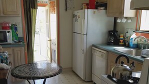 Een functionele keuken met een koelkast, fornuis, magnetron en een eettafeltje.