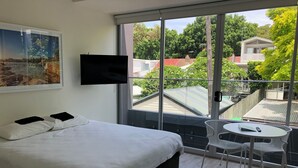 A modern hotel room with a large bed, a small table, and a TV mounted on the wall.