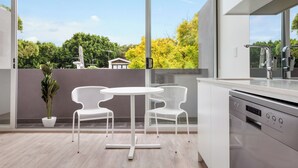 A modern kitchen with a large window, white chairs, and a potted plant.