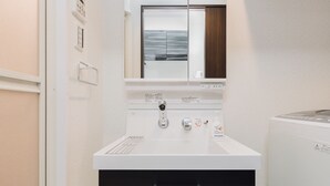 Une salle de bain avec un lavabo blanc, un miroir et une fenêtre.