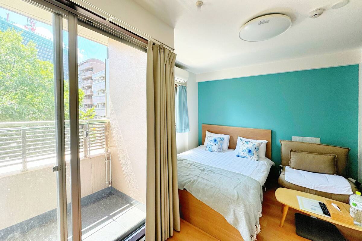 A hotel room with a bed, a desk, and a view of a balcony.