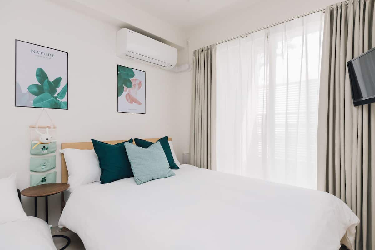A hotel room with a large bed, a bedside table, a wall-mounted TV, and two framed nature posters.
