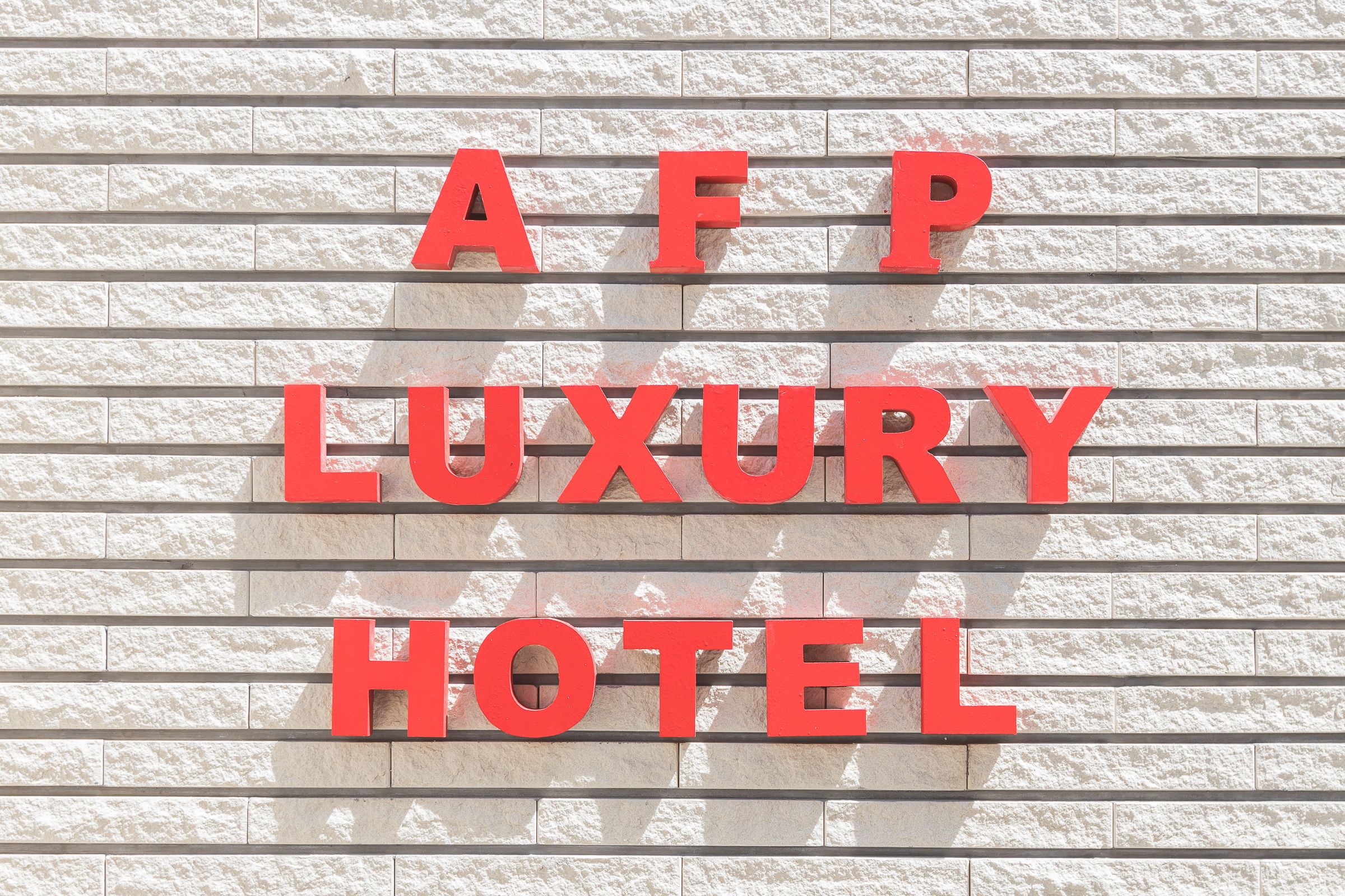 Een bord met de tekst 'AFP LUXURY HOTEL' op een structuurrijke muur.