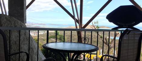 A balcony with a view of a coastal landscape, featuring a round table and chairs.