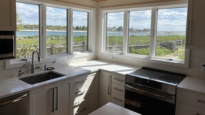 A kitchen with large windows, a sink, and a stove.