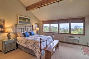 Ein Schlafzimmer mit einem großen Bett, einer Holzbank, einem Nachttisch, einem Fenster mit Aussicht und einem Wandheizkörper.