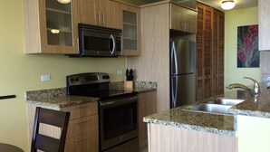 Una cocina con armarios de madera, un refrigerador de acero inoxidable, un microondas y una estufa.