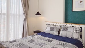 Ein Schlafzimmer mit einem Bett, einer Hängeleuchte, einem Nachttisch und einem gerahmten Bild an der Wand.