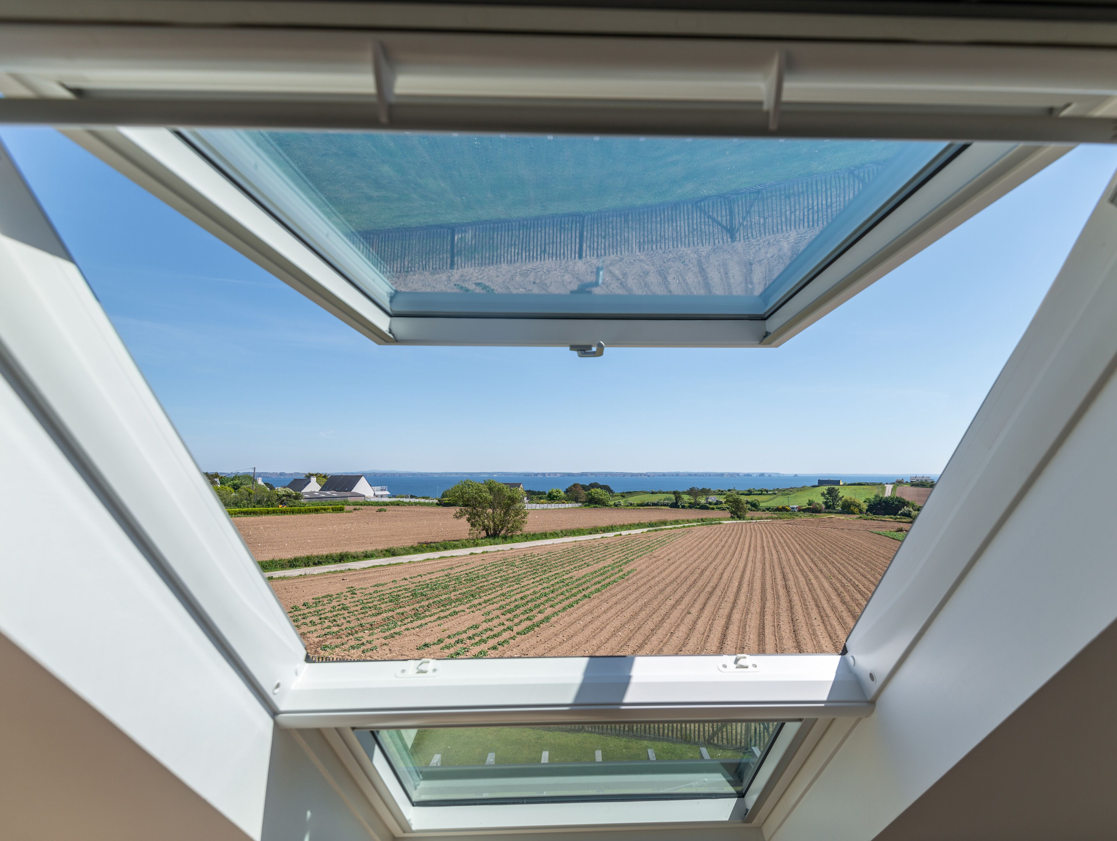 A skylight with a view of a farm and distant landscape.