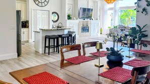 Un coin repas avec une table en bois, des sets de table rouges et un lustre.