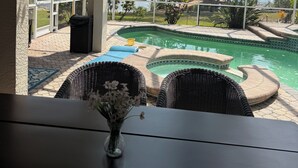 Un patio couvert avec une piscine, du mobilier d’extérieur et une vue sur un lac.