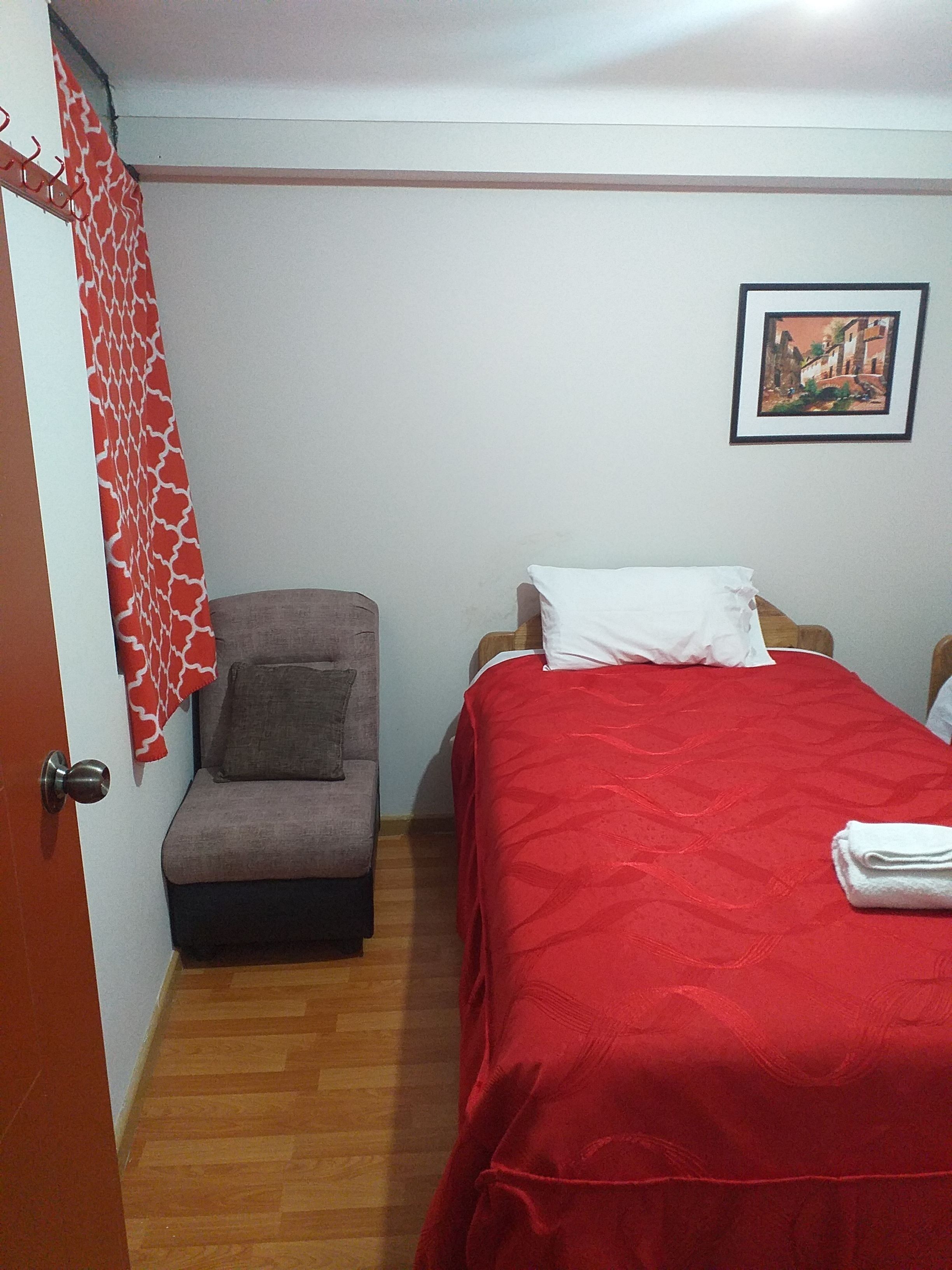 Une chambre à coucher avec un lit, une chaise, une porte et un mur orné d’un tableau.