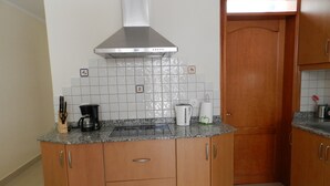Una cocina con encimeras de granito, armarios de madera, campana extractora de acero inoxidable y salpicadero de azulejos.