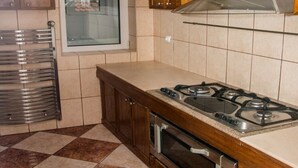 Una cocina con estufa a gas, horno, armarios de madera y ventana con vistas decorativas.