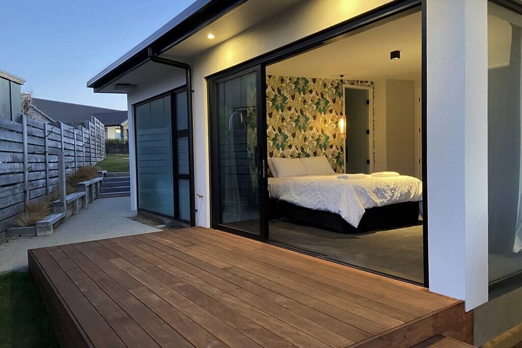 A modern bedroom with a large sliding glass door leading to a balcony.
