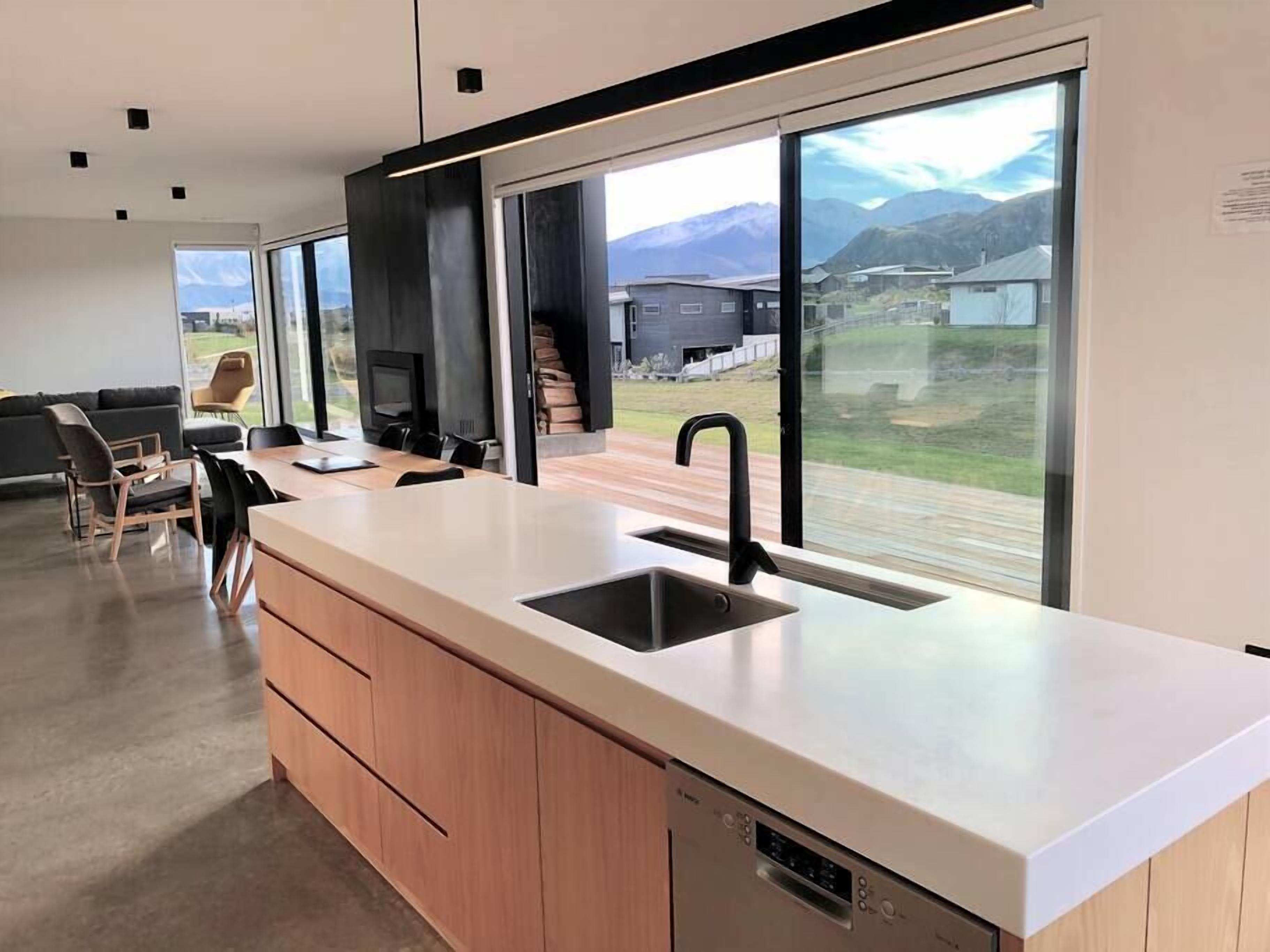 Une cuisine moderne dotée d’une grande fenêtre, de meubles en bois et d’un lave-vaisselle encastré.