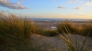 A beach with sand dunes and grass in the foreground, leading to the ocean. - ‘Waterside’ is a 1st floor apartment  on the river in Rye, East Sussex (Rye, East Sussex)