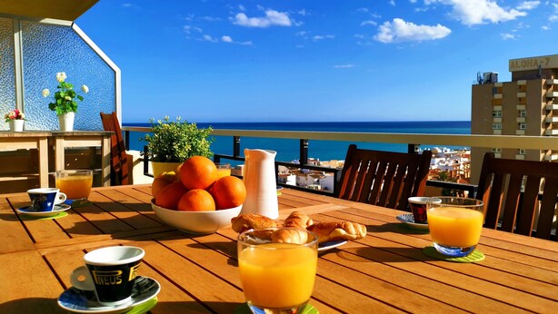 A wooden table with breakfast items and a view of the ocean. - CARIHULA TORREMOLINOS APARTMENT (Torremolinos)
