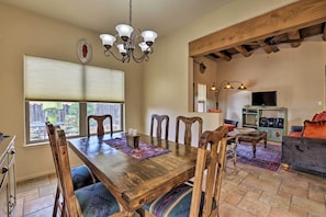 A dining area with a wooden table and chairs, a chandelier, and a television in the background. - 1 Mi to Santa Fe Plaza: Quiet Home w/ Patio (Santa Fe)