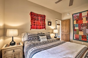 A bedroom with a bed, two bedside tables with lamps, a wooden door, and a wall hanging. - 1 Mi to Santa Fe Plaza: Quiet Home w/ Patio (Santa Fe)