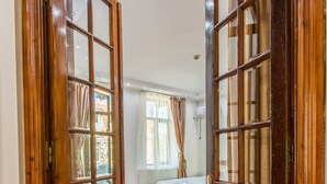 A wooden door leading into a room with a bed and a window with curtains. - Unique apartment situated in the real heart of Bucharest  (Sector 1)