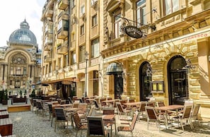A café with outdoor seating, a historic building in the background, and a sign reading "NEGRESCO".