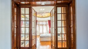 A hallway with wooden doors leading to a bedroom with a bed and a desk. - Unique apartment situated in the real heart of Bucharest  (Sector 1)