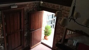 Una stretta scala conduce a una piccola stanza con una porta di legno, una pianta in vaso e un tavolo con tovaglia decorata.