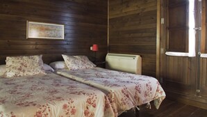 Camera da letto in una baita di legno con un letto, un comodino, una lampada e una porta.