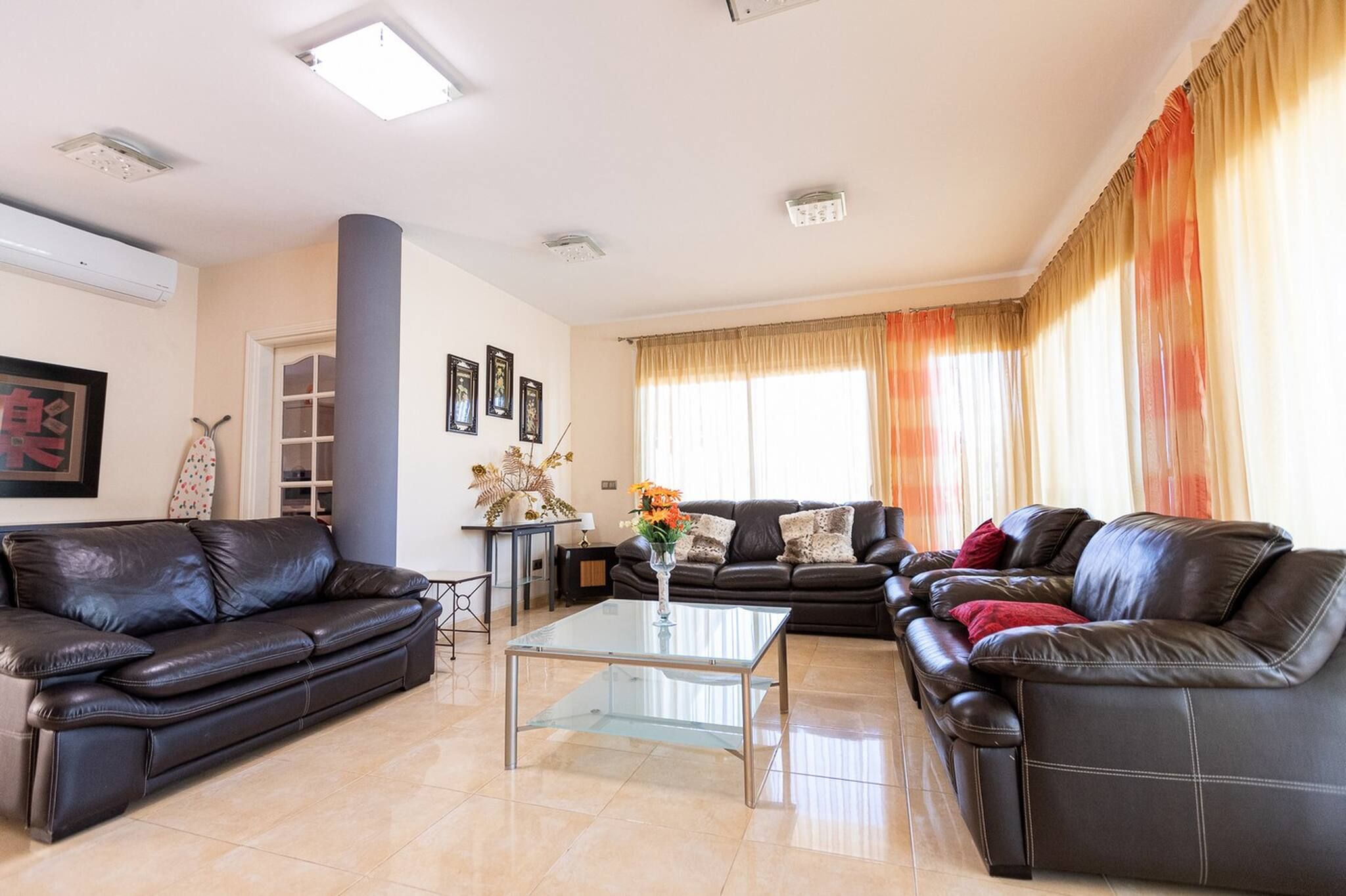 Ein Wohnzimmer mit zwei schwarzen Ledersofas, einem Glastisch und einer dekorativen Vase.