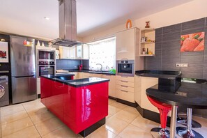 Una cucina moderna con isola centrale, elettrodomestici in acciaio inossidabile e una parete d'accento rossa.